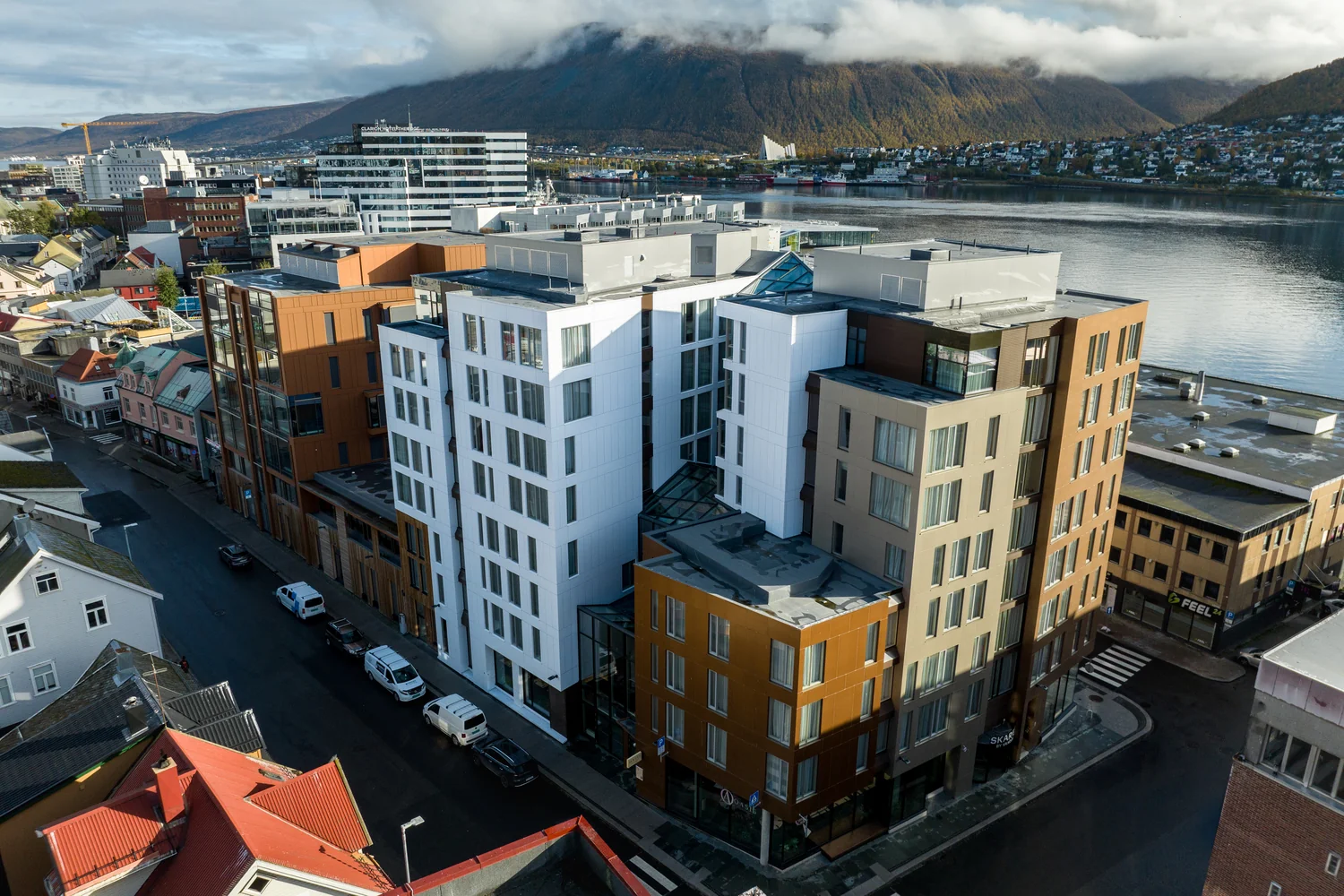 Luftperspektiv av hotell i bymiljø Byhotell i sentral beliggenhet med utsikt mot vann og fjell