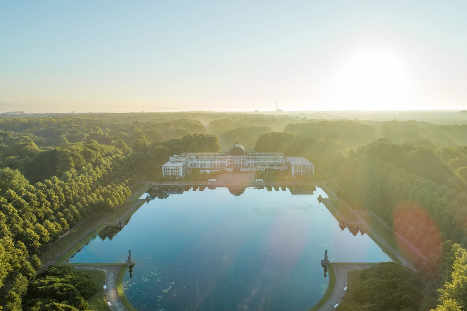 Oversikt over hotellanlegg og omgivelser Hotellanlegg med grøntområde og vannflate sett ovenfra