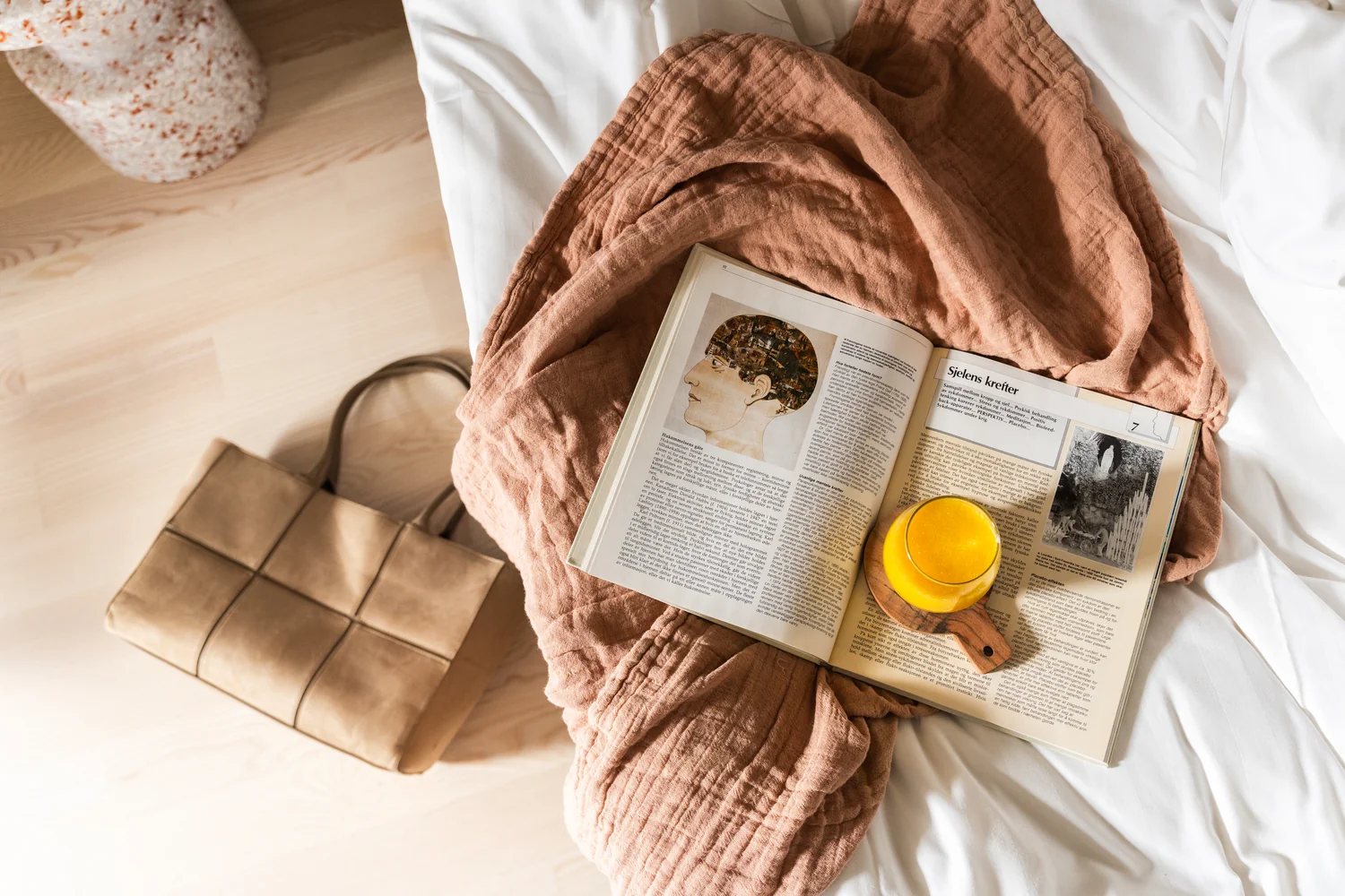 Innbydende hotellrom med rolige detaljer Stilrent hotellrom med seng, sengetøy, bok og fersk juice