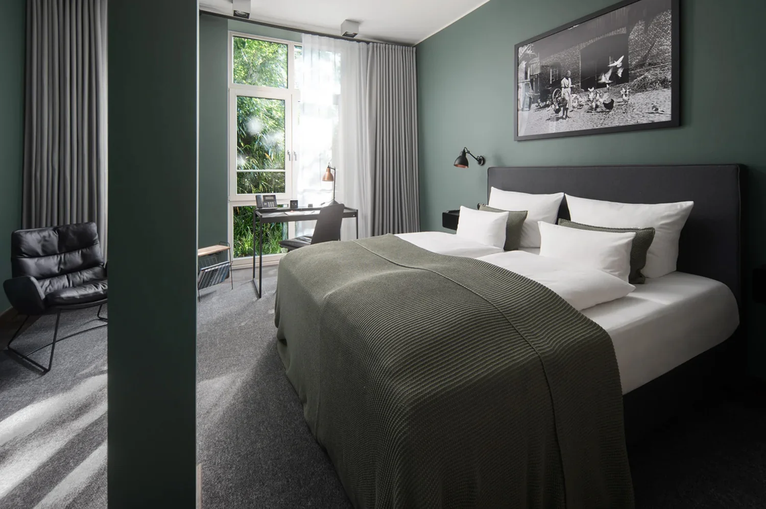 Hotellrom med rolig interiør og arbeidsplass Moderne hotellrom med dobbeltseng, skrivebord og dagslys fra vinduet