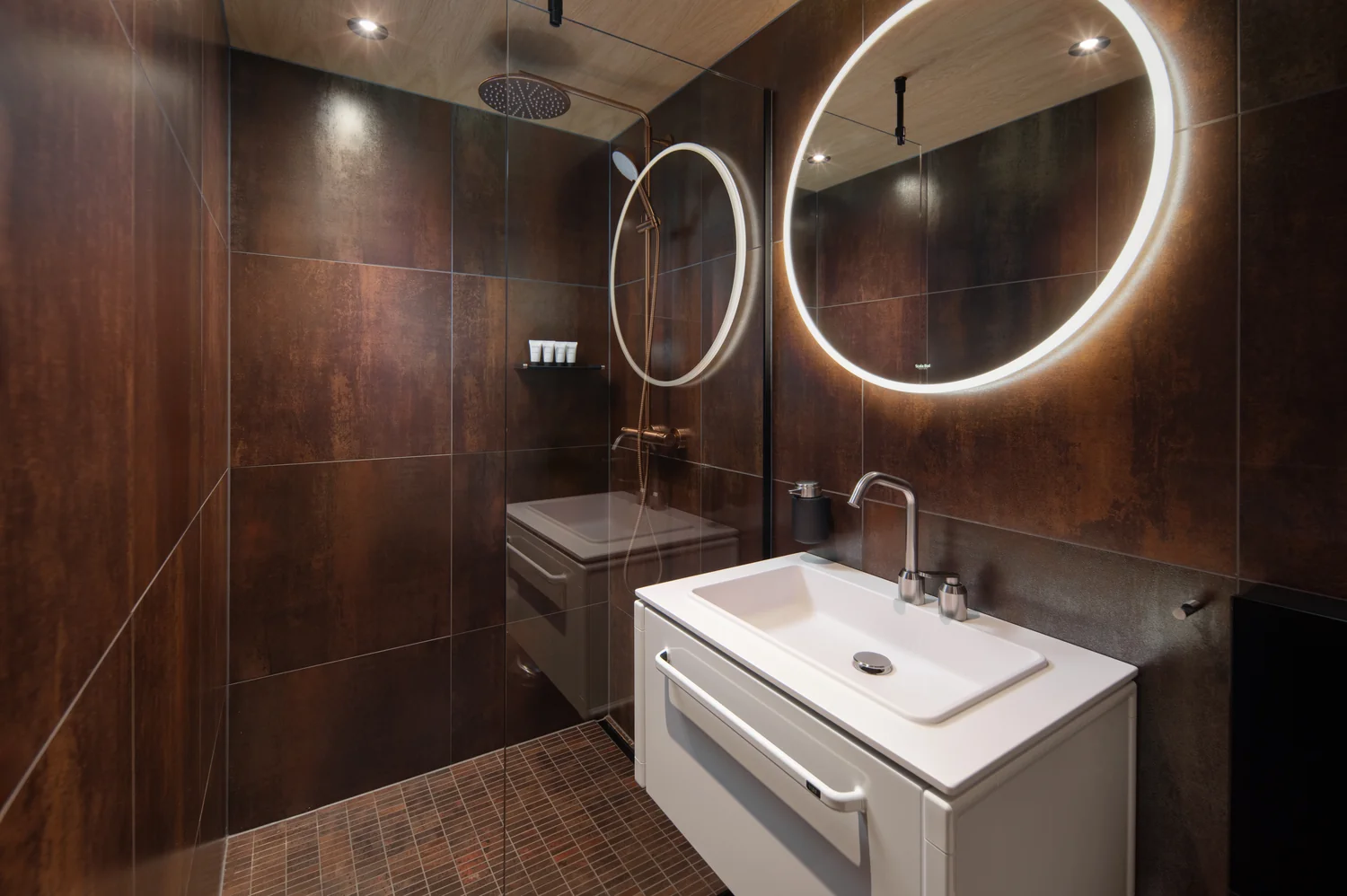 Hotellbad med rene linjer og godt lys Moderne hotellbad med regndusj, speil og gjennomført design